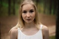 Close up portrait - Beautiful young blonde woman forest nymph in white dress in evergreen wood Royalty Free Stock Photo