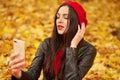 Close up portrait of beautiful young brunette Caucasian woman with her smartphone in hands, taking selfie via phone outdoors in Royalty Free Stock Photo