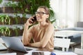 Attractive businesswoman making a call while sitting in front of laptop in the office and working Royalty Free Stock Photo