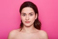 Close up portrait of beautiful young caucasian brunette woman with clean skin after procedures in spa salon, shows bare shoulders Royalty Free Stock Photo