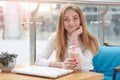 Close up portrait of beautiful young caucasian woman with long blonde hair sitting in cafe, drinking milk cocktail, having rest Royalty Free Stock Photo