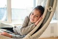 Close up portrait of beautiful young child girl lying at handing chair. Kid relaxing in cozy home Royalty Free Stock Photo