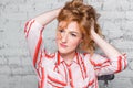 Close-up portrait Beautiful young female student with red curly hair and freckles on her face sitting on a brick wall in gray back Royalty Free Stock Photo