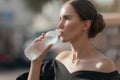 Close-up portrait of a beautiful young girl drinking water from the bottle. Street portrait. Royalty Free Stock Photo