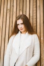 Close up portrait of beautiful young girl with long brown hair on wooden background of planks, winter or autumn outdoor photoshoot Royalty Free Stock Photo