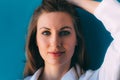 Close-up portrait of beautiful young happy woman on blue background, with hand over head. Royalty Free Stock Photo