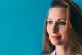 Close-up portrait of beautiful young happy woman on blue background, with space for slogan or text. Nice makeup on face. Royalty Free Stock Photo