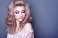 Beautiful young model with colorful artistic make up and wavy hairstyle looking down