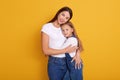 Close up portrait of beautiful young mother and her charming little daughter, stand smiling against yellow studio wall, woman Royalty Free Stock Photo