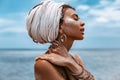 Close up portrait of beautiful young tribal woman in turban at blue sea and sky background