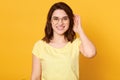 Close up portrait of beautiful young woman with dark hair looking at camera with charming cute smile while posing against yellow Royalty Free Stock Photo