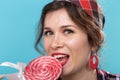 Close up portrait of beautiful young woman eating lollipop over blue background Royalty Free Stock Photo