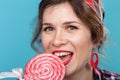 Close up portrait of beautiful young woman eating lollipop over blue background Royalty Free Stock Photo