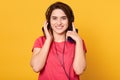 Close up portrait of beautiful young woman listening music via headphone and mobile phone, looking directly at camera and smiling Royalty Free Stock Photo