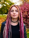 Close-up portrait of beautiful young woman with long pink dreadlocks in black clothes in a park in autumn. Retouching the skin. Royalty Free Stock Photo