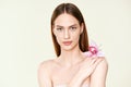 Close up portrait of beautiful young woman with natural make up and orchid in hand Royalty Free Stock Photo