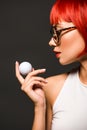 close-up portrait of beautiful young woman with red bob cut and stylish eyeglasses holding golf ball Royalty Free Stock Photo