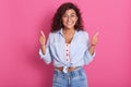 Close up portrait of beautiful young woman showing thumbs up sign, wearing stylish outfit and rounded glasses, having dark wavy Royalty Free Stock Photo