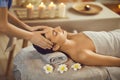 Close up photo of pretty young woman lying with closed eyes and having face or head massage in spa Royalty Free Stock Photo