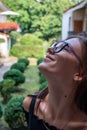 Close up portrait of beutiful brunette girl in glasses that lookes up, green patio on the background Royalty Free Stock Photo