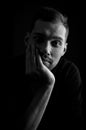 Close up portrait in black and white of a young man holding his face in his hand and looking bored Royalty Free Stock Photo