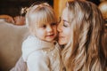 Close-up portrait of a blond little girl and her young mother hugging at home. Motherhood, childhood, family, happyness and trust