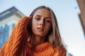 Close up portrait of blonde pretty woman in orange knitted warm sweater. Royalty Free Stock Photo