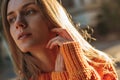 Close up portrait of blonde pretty woman in orange knitted warm sweater. Royalty Free Stock Photo