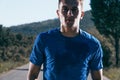 Close up portrait of a blonde, sweaty male runner athlete. Running on an empty road in the woods