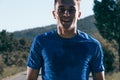 Close up portrait of a blonde, sweaty male runner athlete. Running on an empty road in the woods