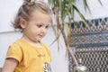 Close-up portrait of a blonde toddler girl with downcast eyes