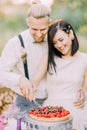 The close-up portrait of the blurred newlywed couple cutting the wedding cake with cherries and strawberries. The Royalty Free Stock Photo