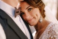 Close-up portrait of a bride looking at the camera, laid her head on the groom`s chest. Beautiful wedding couple. Fine