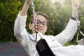 Close up portrait of a brunette child enjoying on a swing wearing a fashion white sailor suit for his first communion