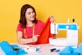 Close up portrait of brunette European female seamstress with tapes mesure on neck, wears casual red t shirt, isolated over yellow Royalty Free Stock Photo