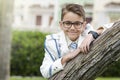 Close up portrait of a brunette little boy leaning on a tree trunk wearing a fashion white sailor suit for his first communion Royalty Free Stock Photo