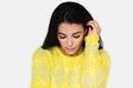 Close up portrait of brunette pretty dreamy woman looking down with hand on hair. Young beautiful woman wearing yellow sweater Royalty Free Stock Photo