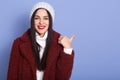 Close up portrait of brunette woman with long dark hair and red pomade, female wearing maroon faux fur coat and white winter cap, Royalty Free Stock Photo