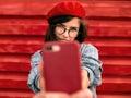 Close-up portrait of brunette young woman smiling broadly, taking self portrait, wearing blue shirt, red beret hat and glasses, Royalty Free Stock Photo