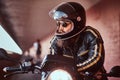 Close-up portrait of a brutal bearded biker in helmet and sunglasses dressed in a black leather jacket sitting on a Royalty Free Stock Photo