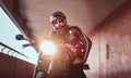 Close-up portrait of a brutal bearded biker in helmet and sunglasses dressed in a black leather jacket sitting on a Royalty Free Stock Photo