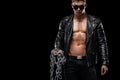 Men fashion. Close-up portrait of a brutal and fit man topless in a leather jacket with chains. Athlete bodybuilder on