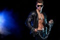 Men fashion. Close-up portrait of a brutal and fit man topless in a leather jacket with chains. Athlete bodybuilder on