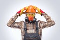 Close-up portrait of a builder with protective glasses, respirator and helmet indoors.