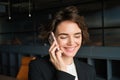 Close up portrait of businesswoman talking on mobile phone, has her smartphone near ear, answers a call, stands in Royalty Free Stock Photo