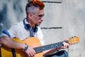 Close up portrait of busker singing and playing guitar on the streets. Caucasian man playing the guitar outdoors