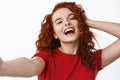 Close up portrait of carefree and happy ginger girl, touching her curly natural hair and laughing while taking selfie Royalty Free Stock Photo