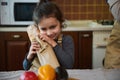 Close-up portrait of a cute little girl hugging a loaf of sourdough bread from family bakery while unpacking grocery bag Royalty Free Stock Photo