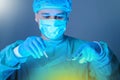 Close-up portrait of a caucasian doctor surgeon, in a sterile suit, mask, holding a scalpel and needle holder with a needle, Royalty Free Stock Photo