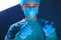 Close-up portrait of a caucasian doctor surgeon, in a sterile suit, mask, holding a scalpel and needle holder with a needle, Royalty Free Stock Photo